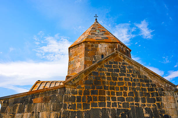 Sevan Monastery Sevanavank with a steeple and a cross on top. The building is old and has a lot of character