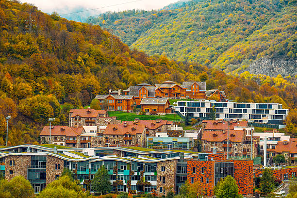 A small town with houses and a church. The houses are mostly brown and white. The town is surrounded by trees and mountains