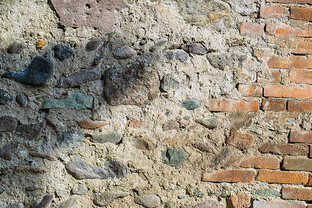 A old wall made of bricks and stones with a shadow on it. The wall appears to be old and worn, with some of the bricks missing or chipped