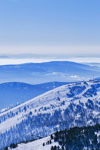 istock View from mount peak Mystag on Green mount, Altai mountains covered snow forest in soft blue haze, nature landscape. Peaks fades in distance under clear winter blue sky, natural gradient tones. 2244262937