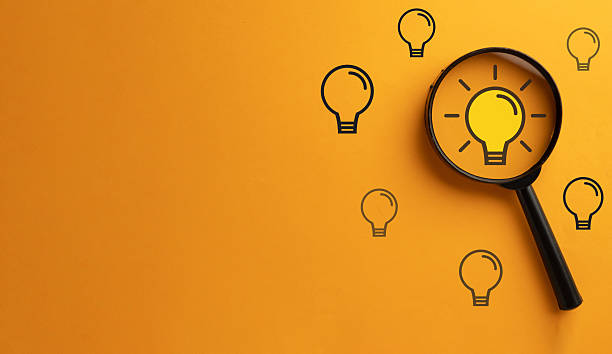 istock Finding an idea concept, magnifying glass focusing on a glowing lightbulb for creativity, innovation, and solutions. 2244272105
