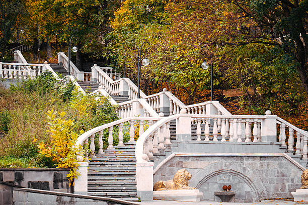 A stone staircase with a stone balustrade leading to a fountain. The balustrade is covered in leaves, giving the scene a serene and peaceful atmosphere