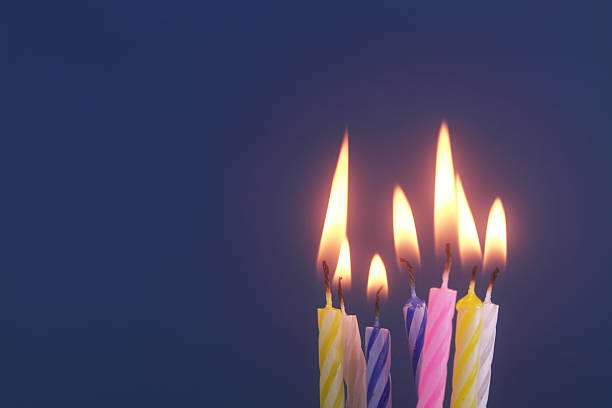 istock Several colourful birthday cake candles burning on blue 2244276501