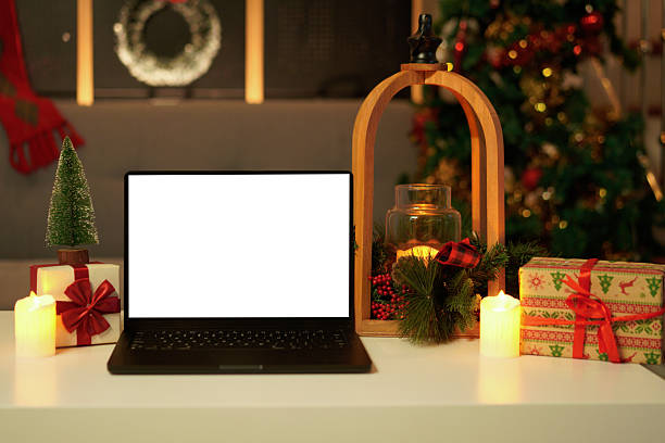istock Front view of white screen laptop in home with Christmas tree warm light. Remote work. freelance. Work from home. Telework. 2244277411