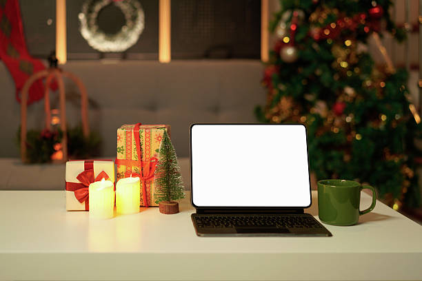 istock Blank display screen digital tablet and cup of hot chocolate on white table in decorated living room for Christmas 2244277414