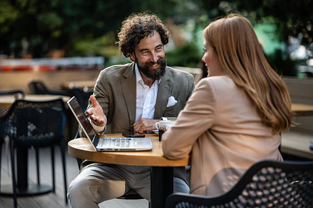 istock Business people discussing work at outdoor cafe using laptop 2244277516