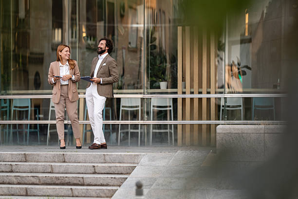 istock Business people talking and laughing outside office building 2244278479