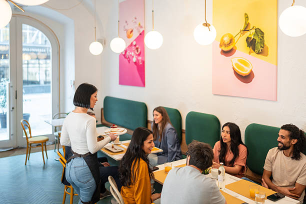 istock Caucasian Waitress Serving Desserts in Bright Cozy Bistro with Cheerful Diverse Diners 2244279238