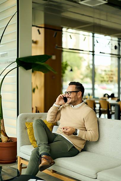 istock Relaxed Businessman On Phone In Modern Office Lobby Sitting On Light Gray Sofa 2244280328