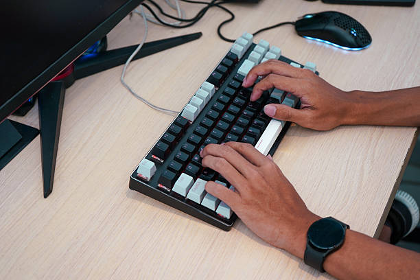 istock messy computer desk with tangled cables, a mouse, and a keyboard, while a male hands are typing on the keyboard, showing the disorganized workspace 2244280915