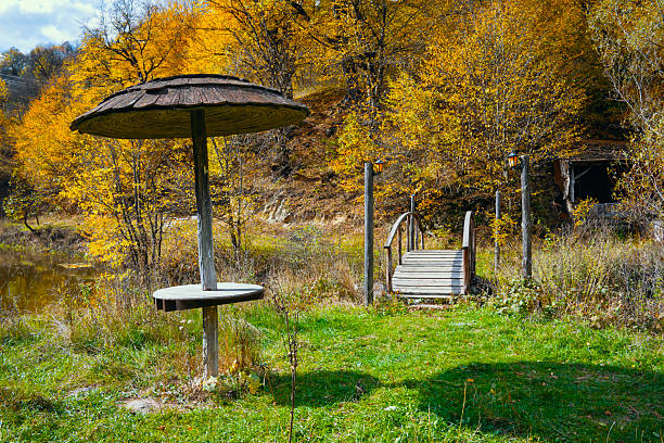 A wooden bench sits in a grassy field next to a small table. The table is covered with a tarp and the bench is empty. The scene is peaceful and serene