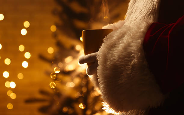 istock Santa Claus with Hot Drink by Christmas Tree Lights 2244282552
