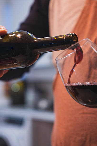 istock Pouring red wine from bottle into glass 2244282631