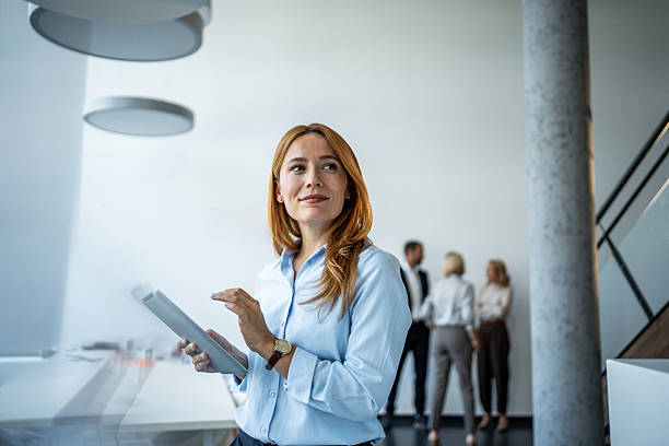 istock Businesswoman looking away while holding digital tablet in office 2244283877