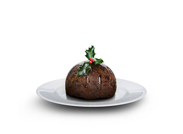 istock Looking down on a round plate with a sprig of holly and a traditional Christmas pudding soaked in brandy. 2244285221