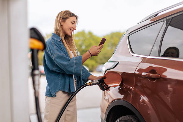 istock Smiling Woman Refueling Car While Using Phone 2244287814