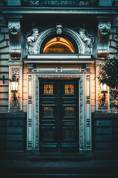Riga, Latvia – July 29, 2025: Ornate entrance of a vintage building with illuminated lamps and detailed carvings, creating a warm and inviting atmosphere.