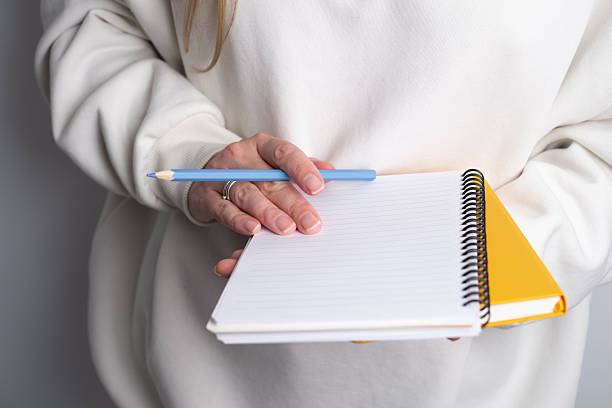 istock Woman writing notes in a notebook. Close-up of hands holding a notebook and writing with a pen. Concept of planning, studying, working, or journaling. 2244290841