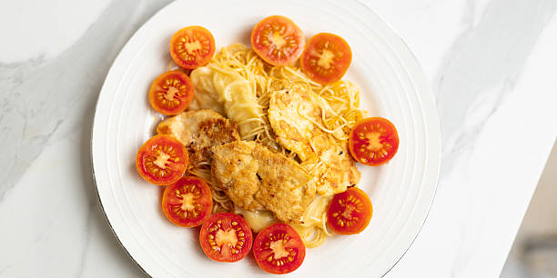 Spaghetti with grilled chicken and cherry tomatoes on white plate