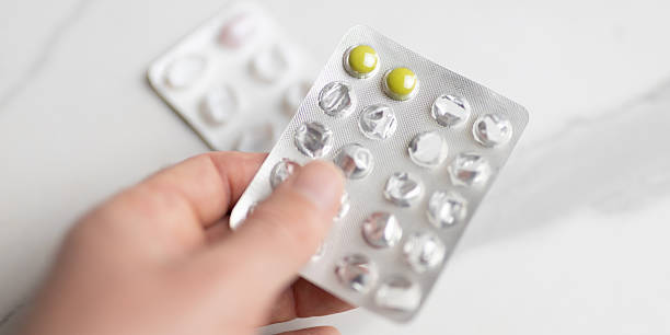 istock Hand holding blister pack with yellow pills on light surface 2244294394