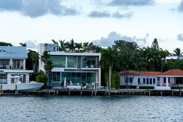 istock Modern waterfront homes with palm trees and a boat. 2244294657