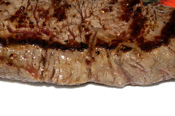 Close up of a cooked grilled steak slice on white background