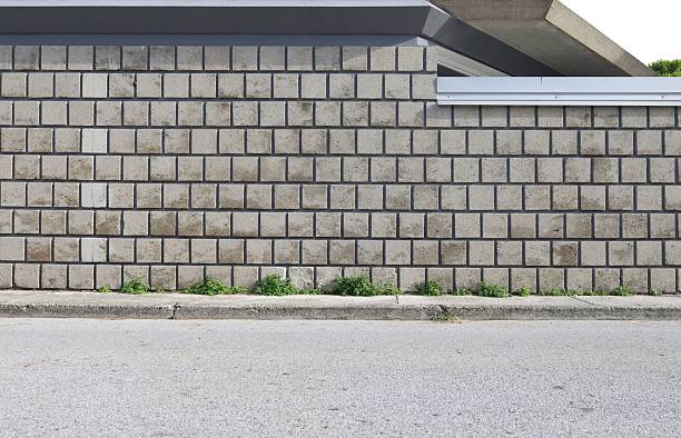 istock Concrete square tile wall at roadside. Sidewalk and street in front. 2244295911