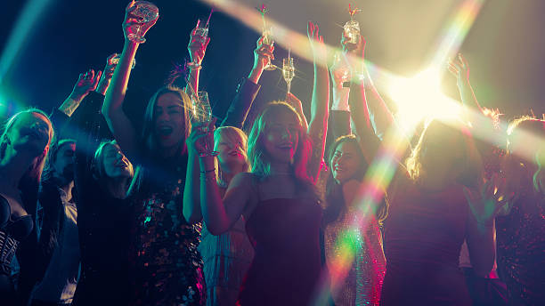 istock Christmas party crowd raising champagne glasses under bright stage lights 2244300035