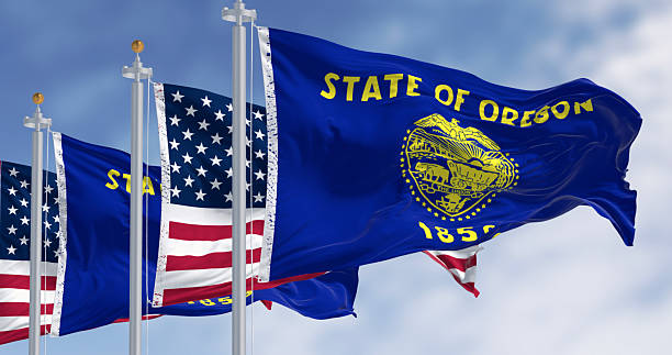 istock Oregon state flags waving in the wind with the american flags on a clear day 2244300786