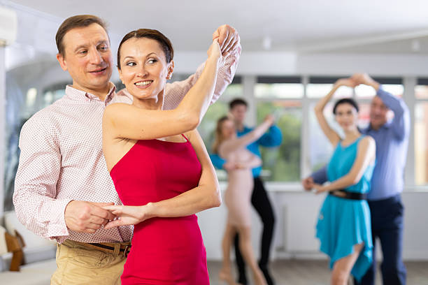 Group of different ages active people in festive clothes dancing dance movements in modern studio