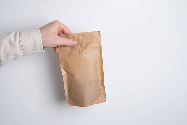 istock Kraft paper packaging in a mans hands. Packaging for coffee, cosmetics. Packing closeup. Product for sale. Online shopping. Boxes with surprise. Delivery service, shipping. Empty, mockup. Eco friendly 2244304805