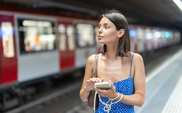 istock Young girl standing on subway platform with phone in hand 2244306042