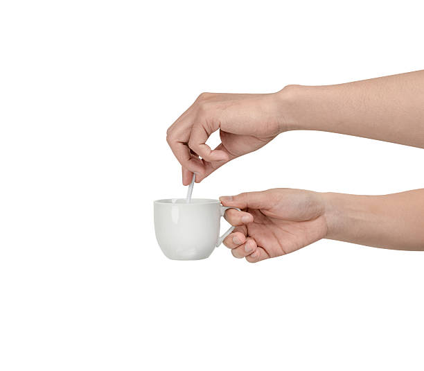 istock A person's hand extending and holding a plain, white ceramic coffee cup with a small white spoon inside. Isolated on a clean white background, this image conveys concepts of service Isolated. 2244306361