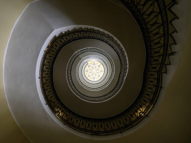 Artistic spiral staircase with intricate railing and central skylight in Ceuta.