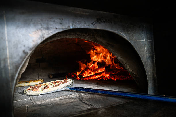 Closeup of a pizza baking inside a hot oven chamber, with glowing flames creating atmosphere and emphasising traditional pizza cooking in a restaurant kitchen.
