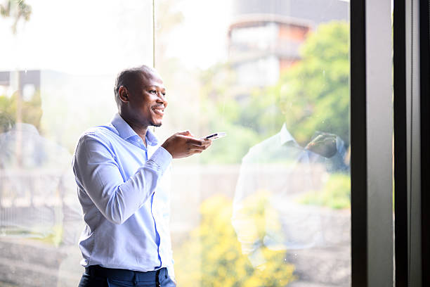 istock Smiling businessman using smartphone for a call near a large window in a luxury hotel interior with nature views 2244310423