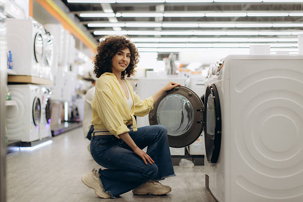istock Young Woman Choosing Washing Machine in Modern Electronics Store 2244316878