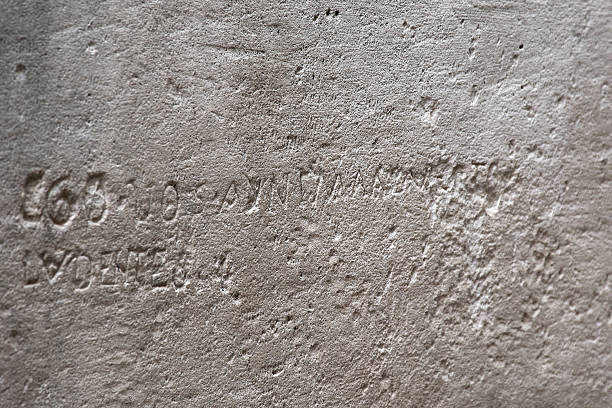 istock Ancient letters and numbers engraved on a gray stone surface 2244318754
