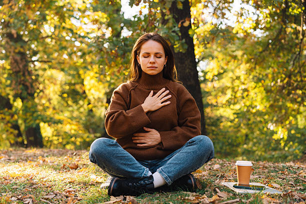 istock Woman in meditative pose outdoors in autumn tree area doing breathing exercise. Nature escape and mental health. 2244319945