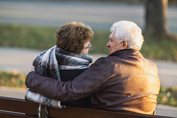 istock Senior Couple Sitting on a Park Bench 2244322234