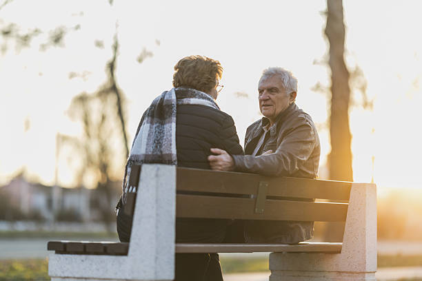 istock Senior Man and Woman Sitting on a Bench and Talking 2244322254