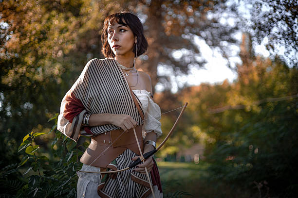 Confident woman archer in golden fall landscape, forest path, concentration and inner strength