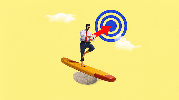 istock Collage art. Businessman balancing on surfboard with tablet and red arrow hitting target under blue sky 2244323092