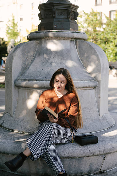 A woman sitting and reading in a public park