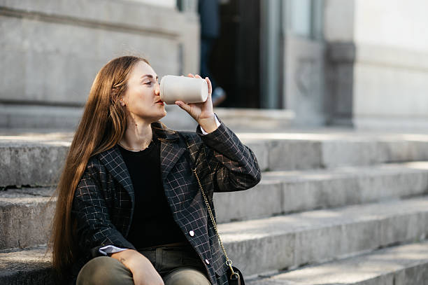 istock Woman drinking from a reusable coffee cup 2244325053