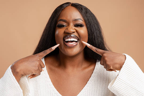 istock Black woman smiling and pointing at white teeth 2244326544