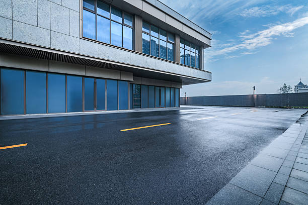 istock Empty wet asphalt road outside of a modern commercial office building. 2244326840