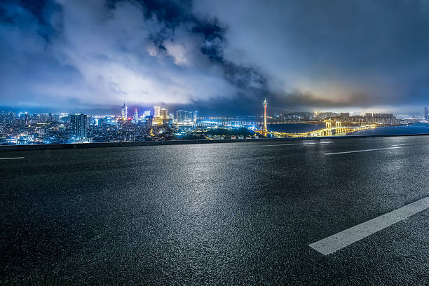 istock Empty asphalt road overlooking the illuminated modern city skyline and bridge at night. 2244326878
