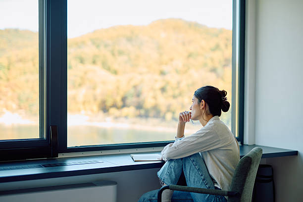 istock Woman looking through window thinking about nature 2244326957