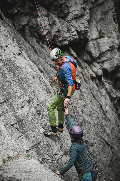 istock Two Climbers Assist Each Other While Climbing a Cliff Face with Ropes and Gear 2244329402